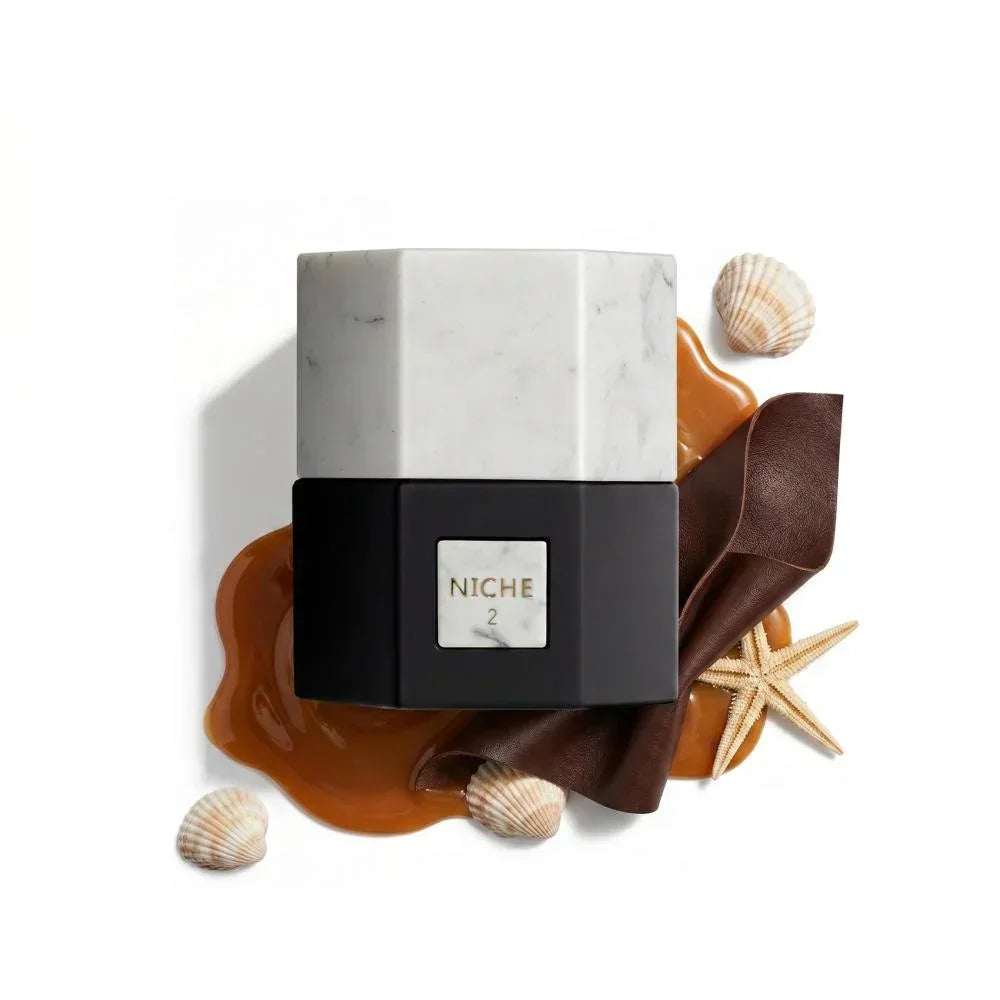 Niche 2 perfume bottle with marble design, surrounded by seashells and amber liquid