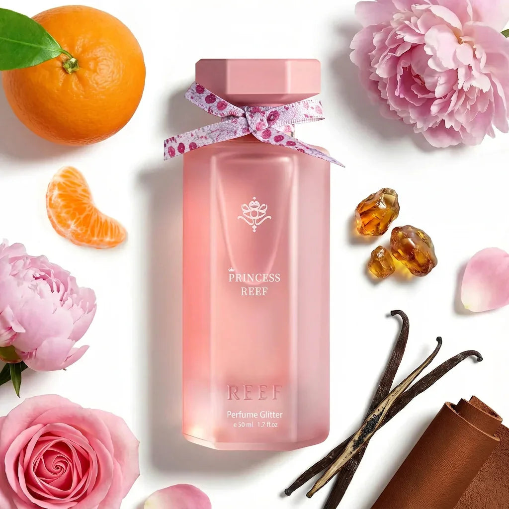 Pink Princess Reef perfume bottle with floral ribbon, surrounded by peonies, oranges, vanilla, and amber